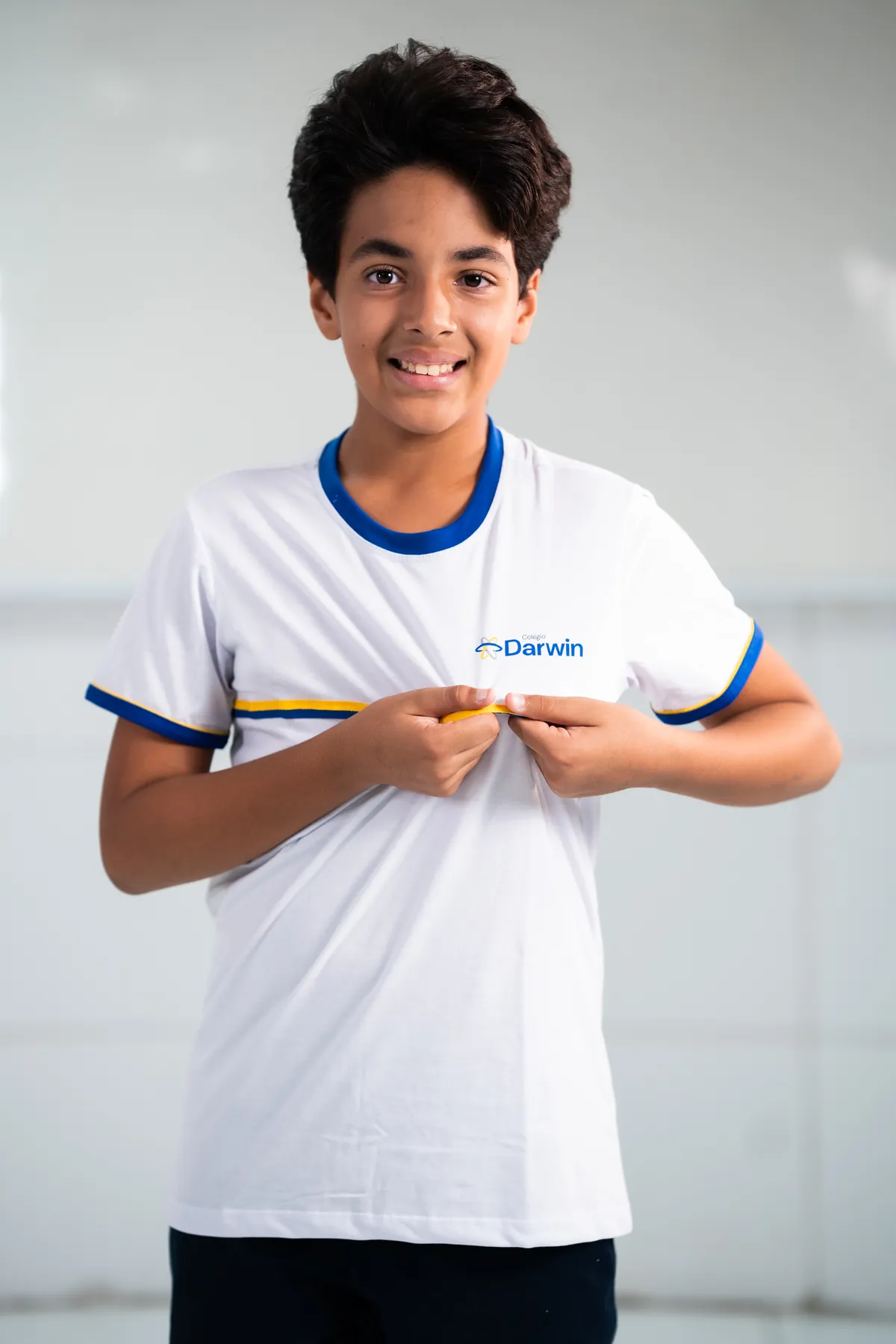Aluno dos Anos Finais sorrindo com uniforme branco do Darwin.