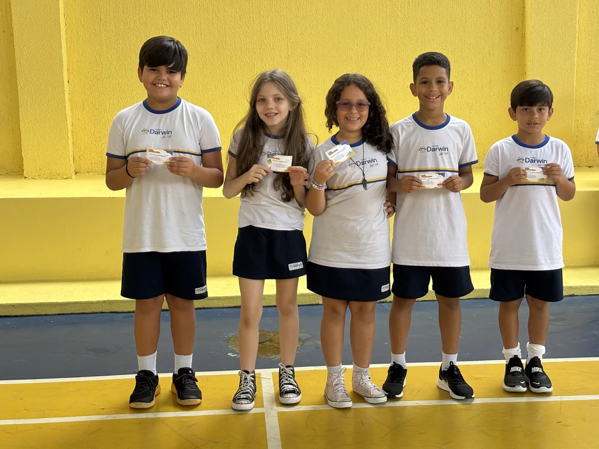 Alunos dos Anos Iniciais mostrando pequenas premiações na quadra.