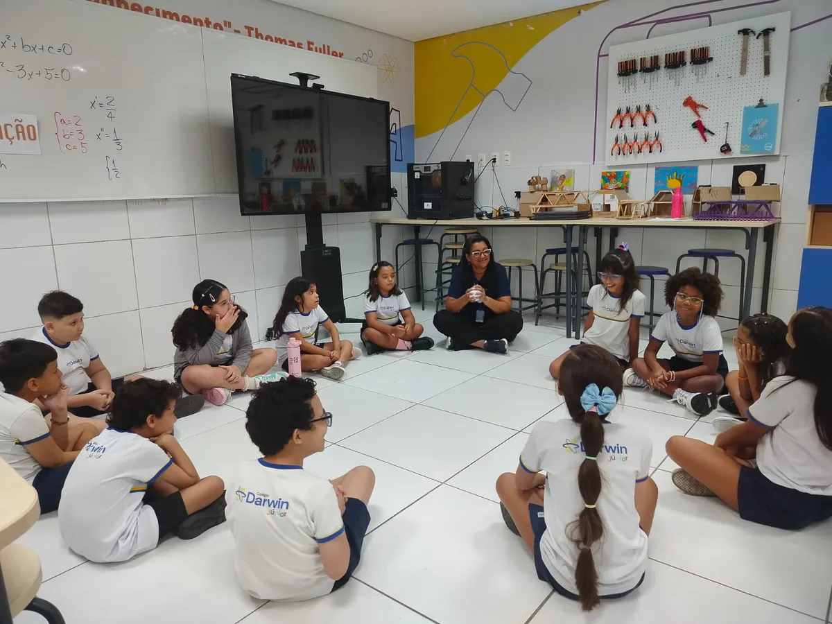 Alunos sentados em círculo no chão do Espaço Maker.