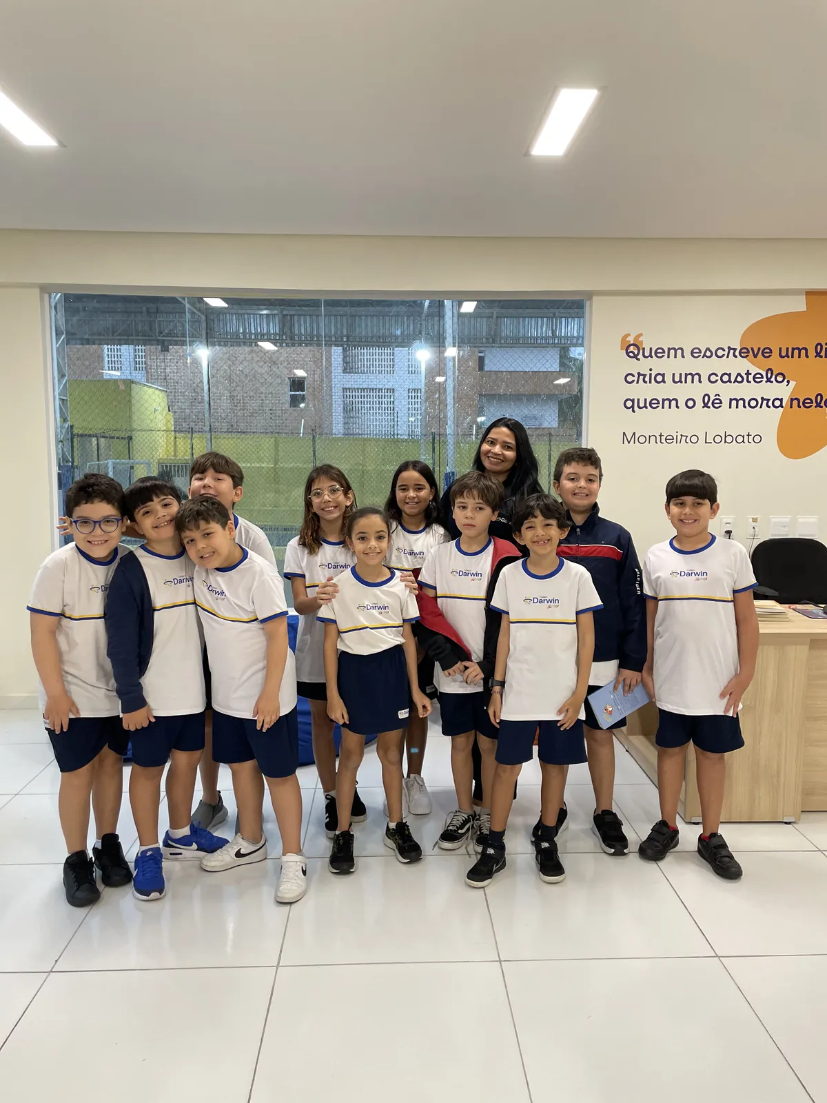 Grupo de alunos com a professora posando juntos em sala de aula.