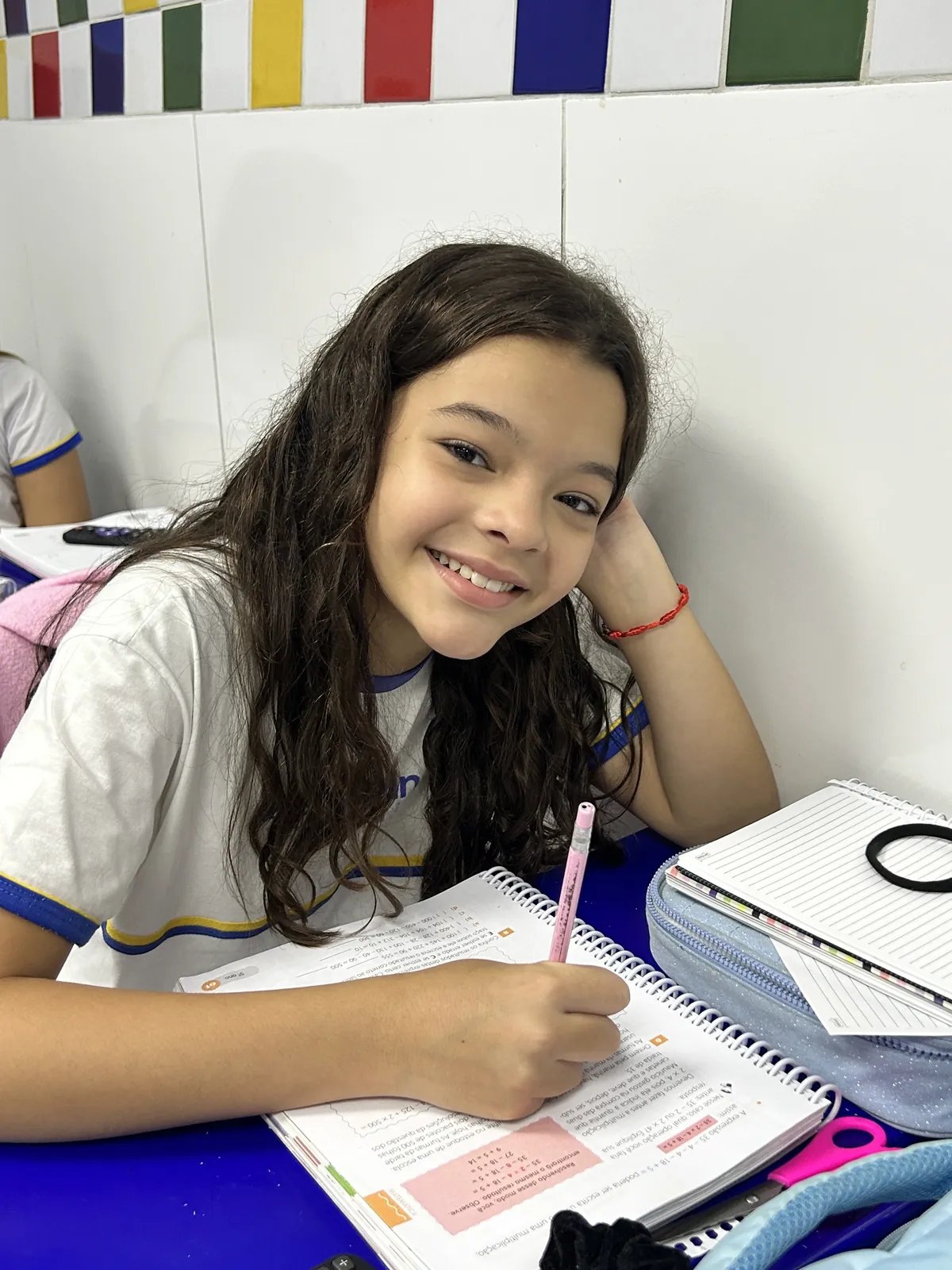 Aluna dos Anos Iniciais escrevendo em apostila durante atividade de leitura.