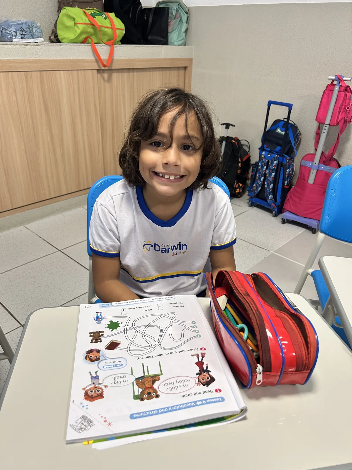 Aluna dos Anos Iniciais com apostila de inglês em sala de aula.