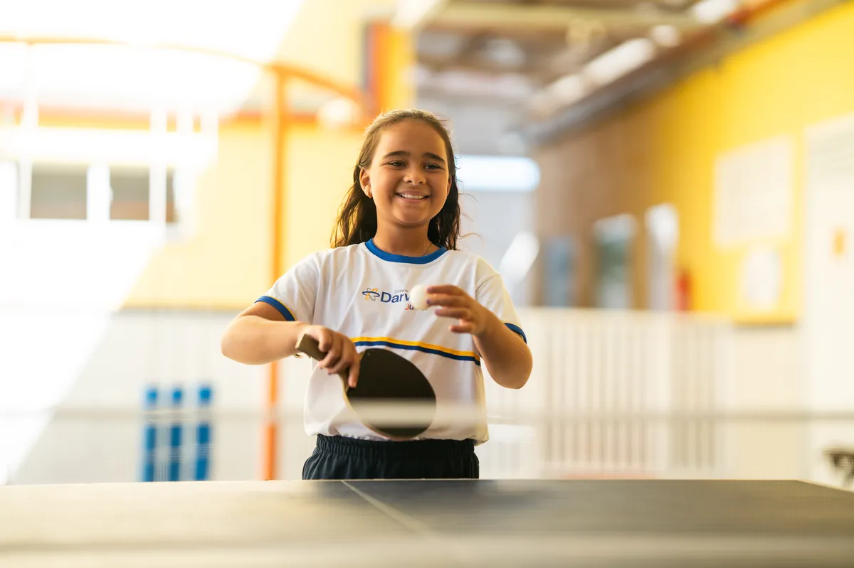 Aluna sorrindo enquanto joga tênis de mesa no Darwin