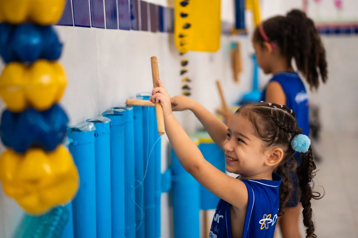 Aluna da Educação Infantil tocando instrumento na aula de música