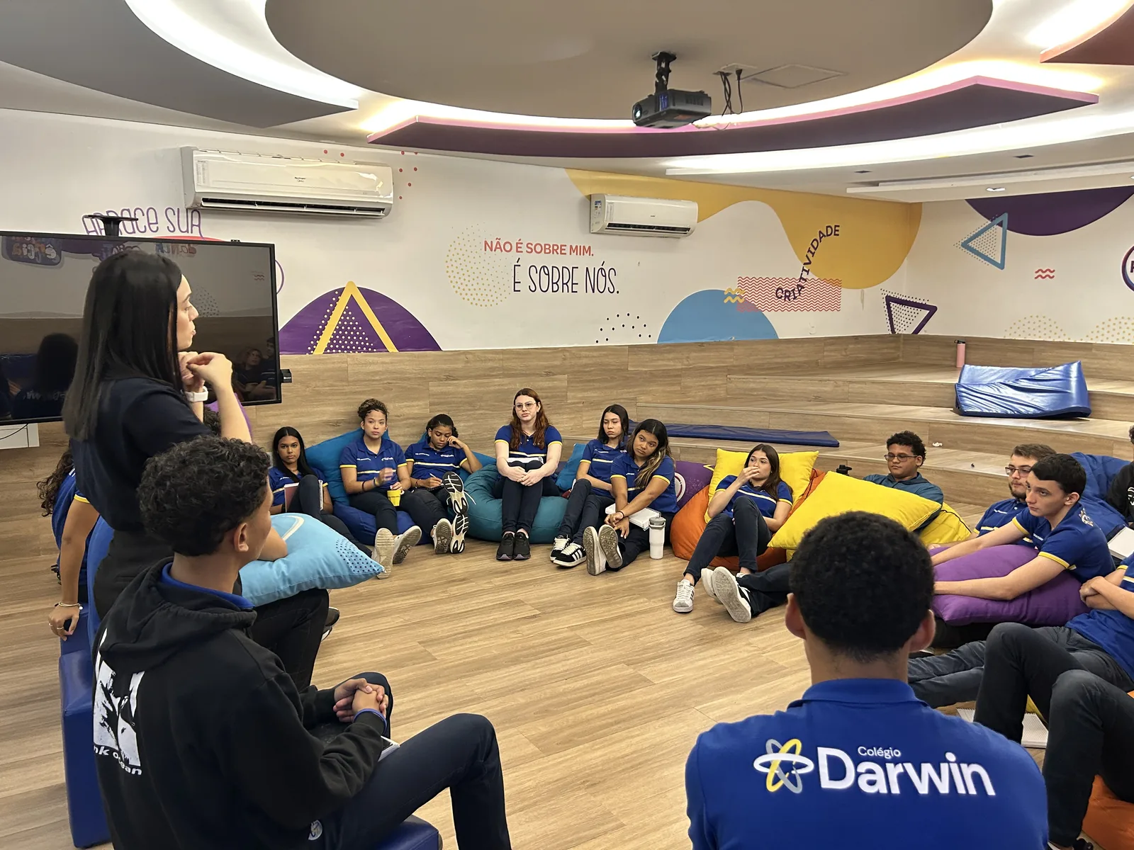 Alunos do Ensino Médio do Darwin em roda de conversa na sala de convivência, sentados em almofadas.