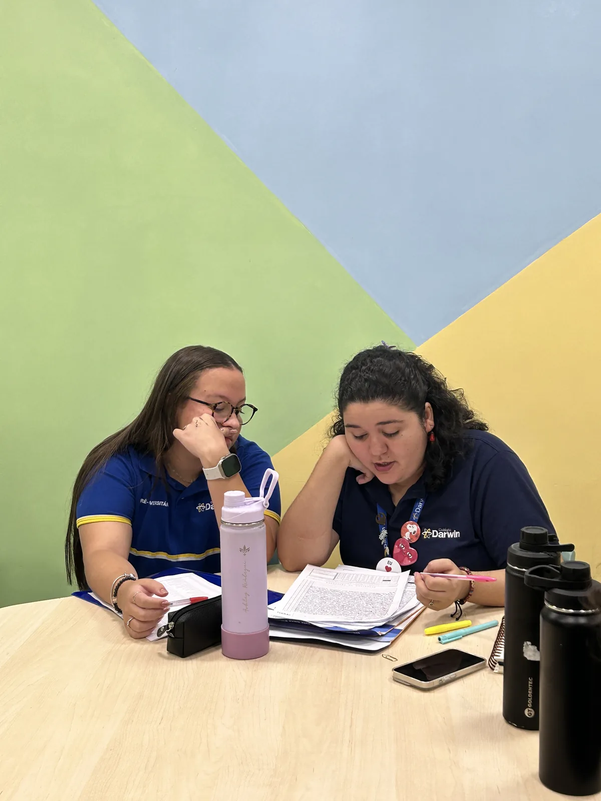 Duas alunas do Ensino Médio do Darwin estudando juntas com material e anotações sobre a mesa.