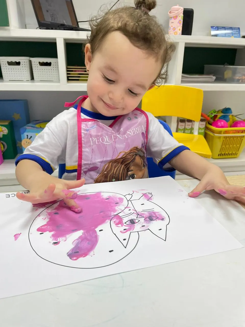 Menina do Infantil pintando com os dedos usando tinta.