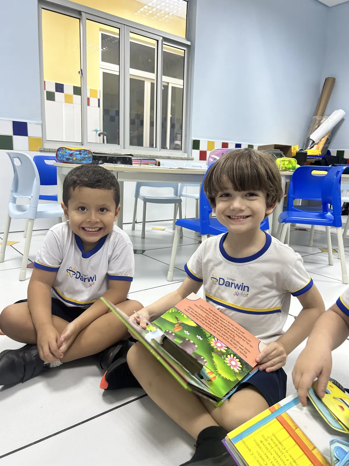Dois meninos do Infantil sentados juntos lendo um livro.