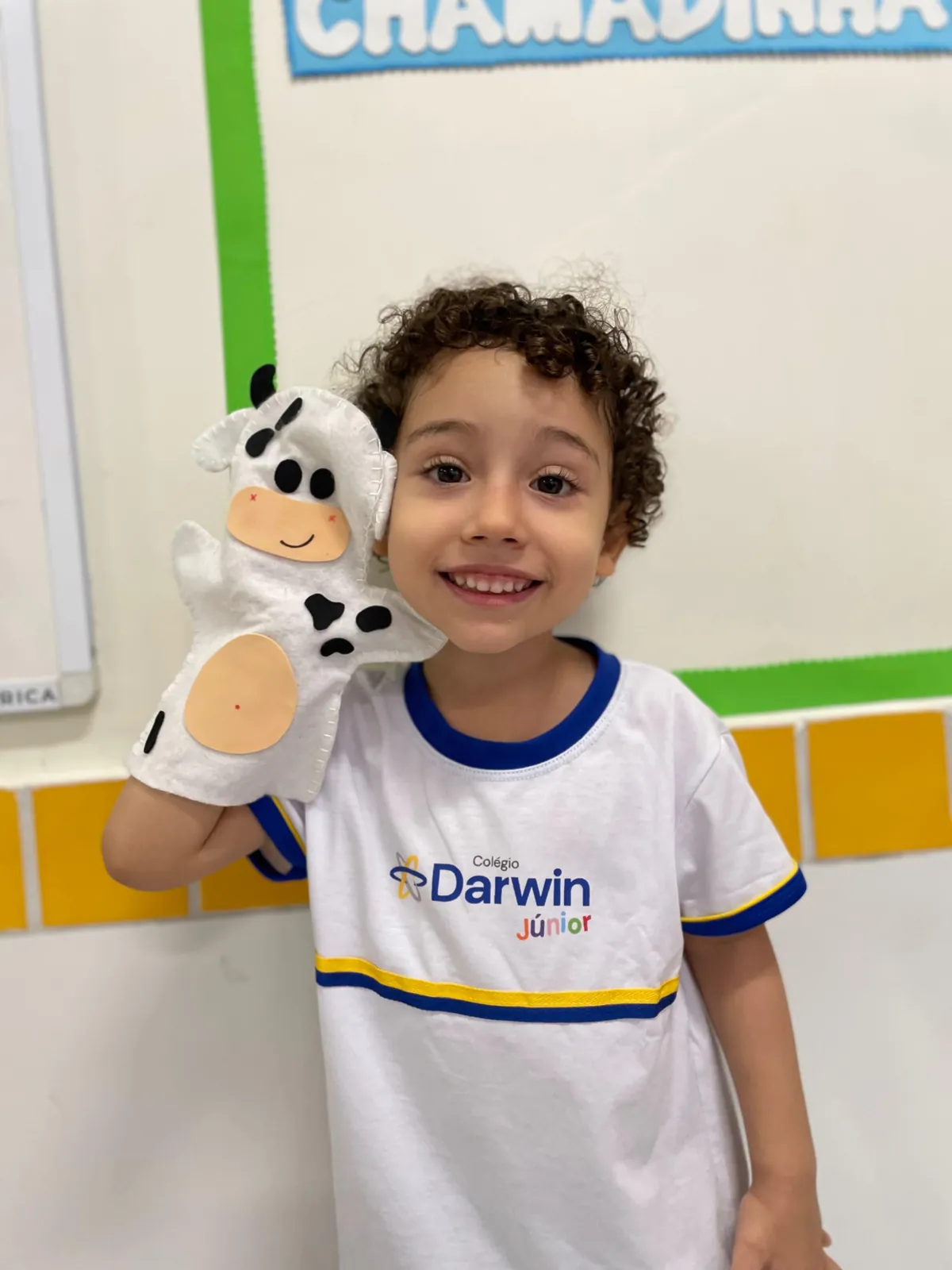 Criança do Darwin Infantil com boneco de mão de vaca.