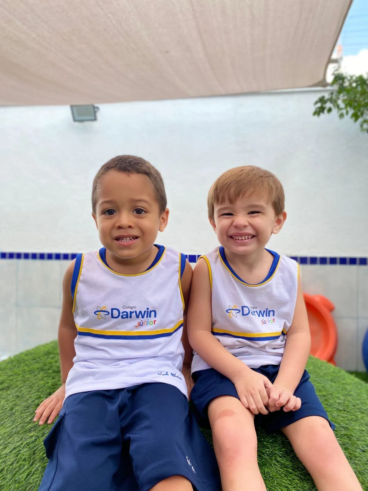 Dois meninos brincando em morrinho gramado da escola.