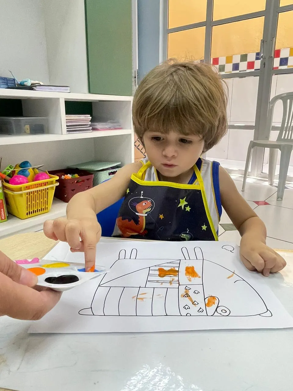 Menino pintando com o dedo em atividade sensorial.