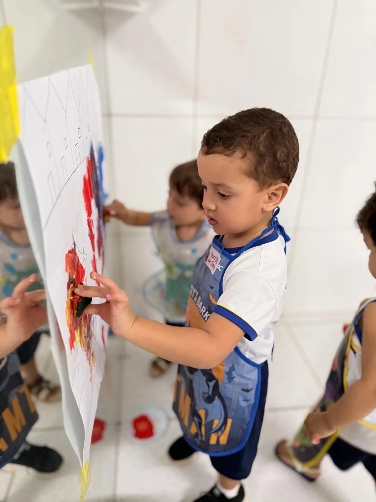 Menino pintando mural em atividade de arte.
