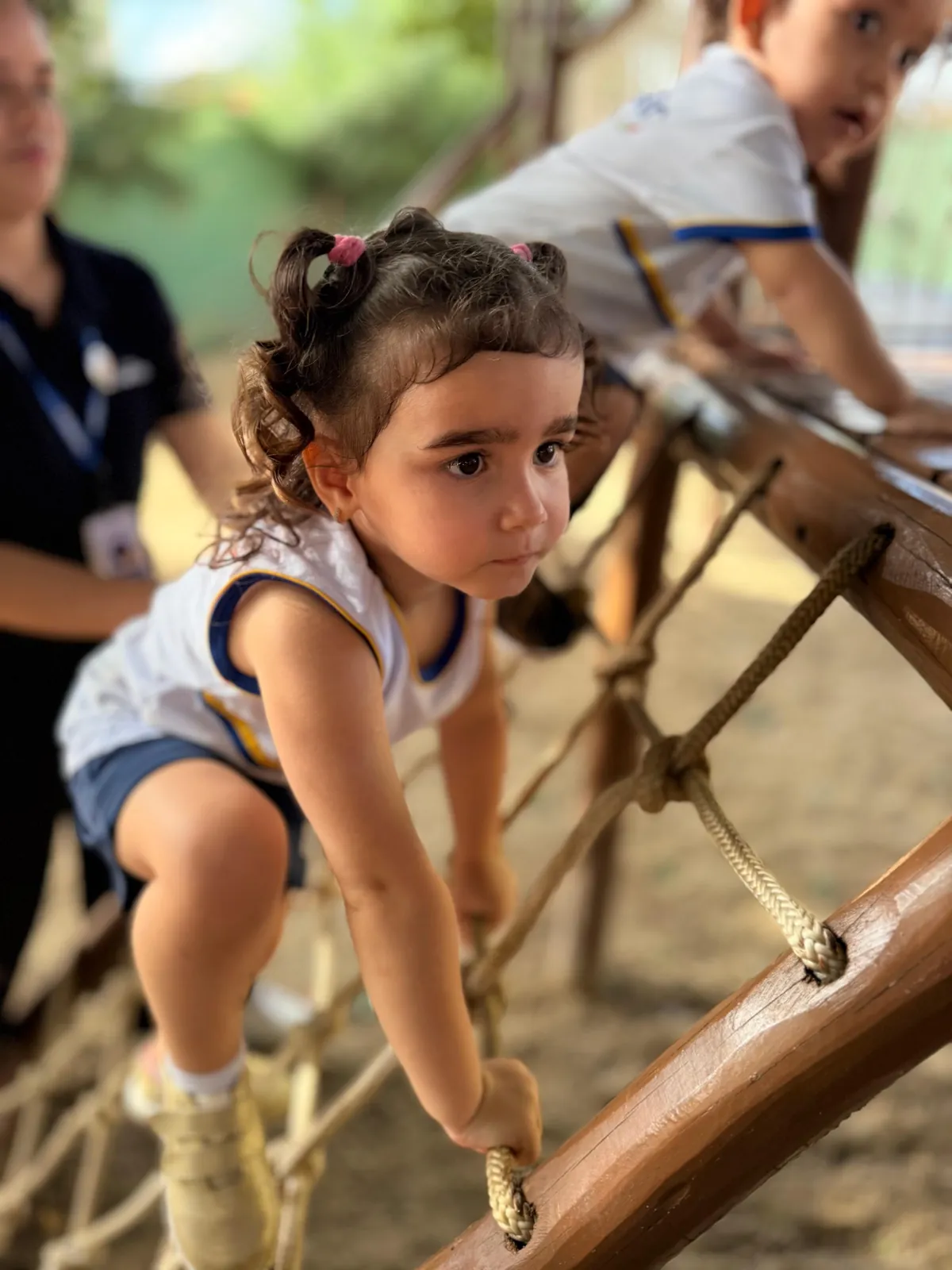 Menina escalando rede de corda no parquinho.