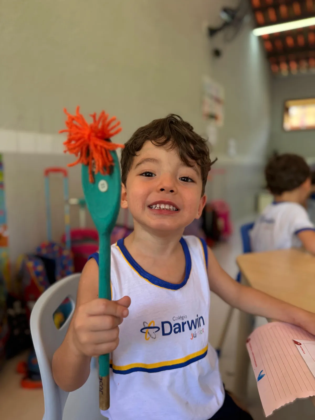 Menino segurando colher de pau com fios laranja.
