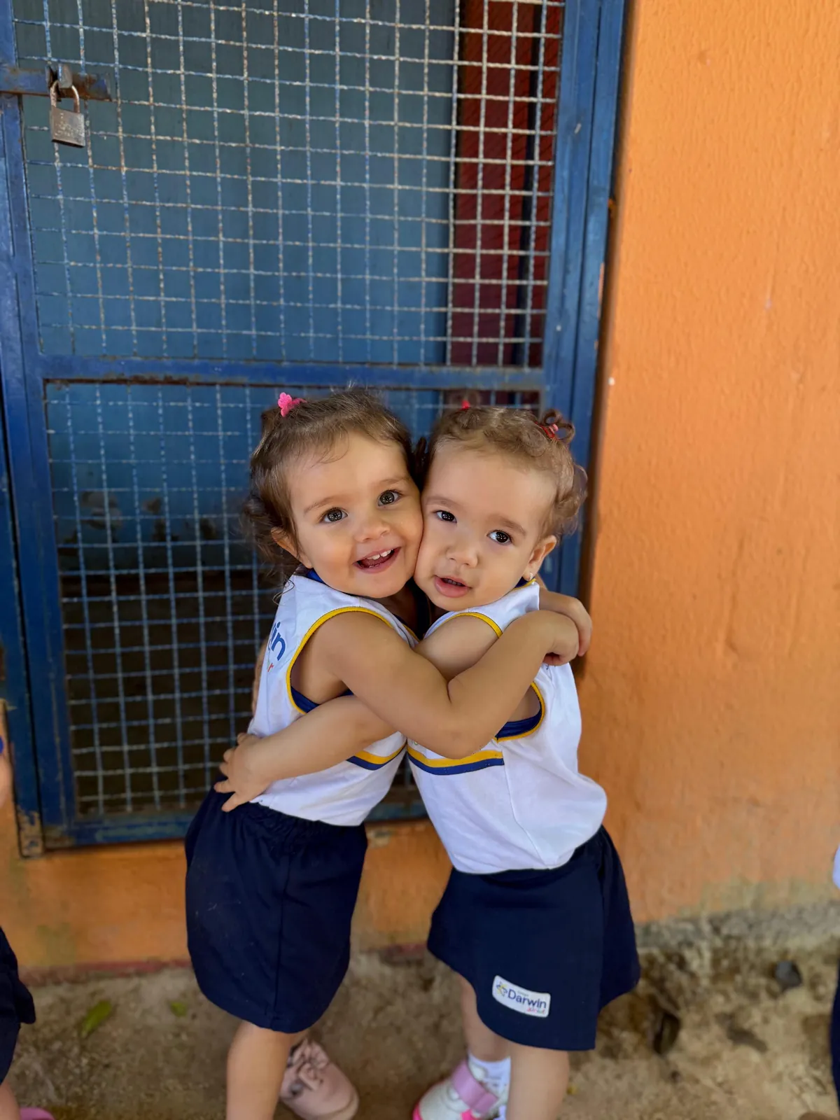 Duas meninas do Darwin Júnior abraçadas com uniforme.