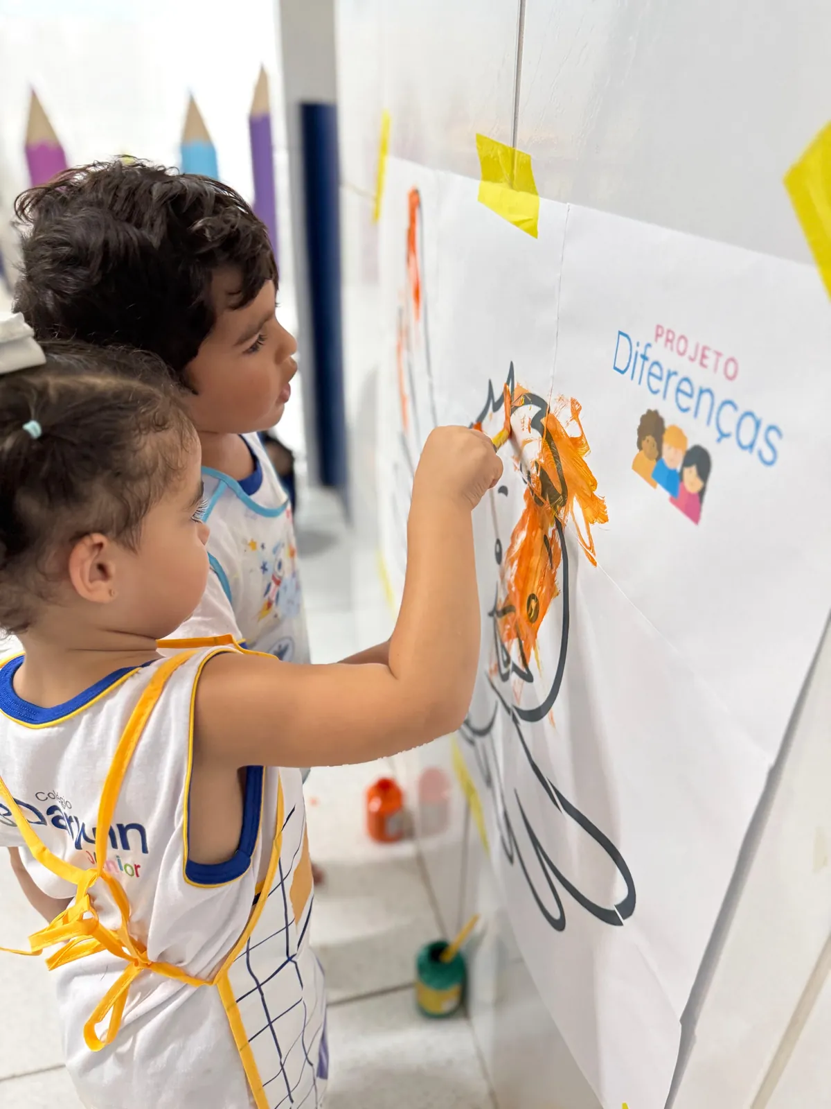Duas crianças pintando mural do Projeto Diferenças.