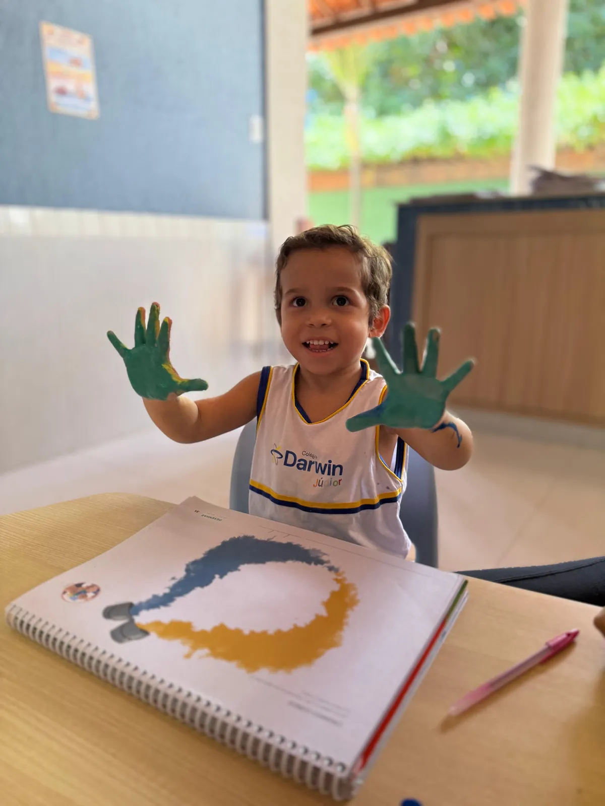 Menino mostrando as mãos com tinta verde.