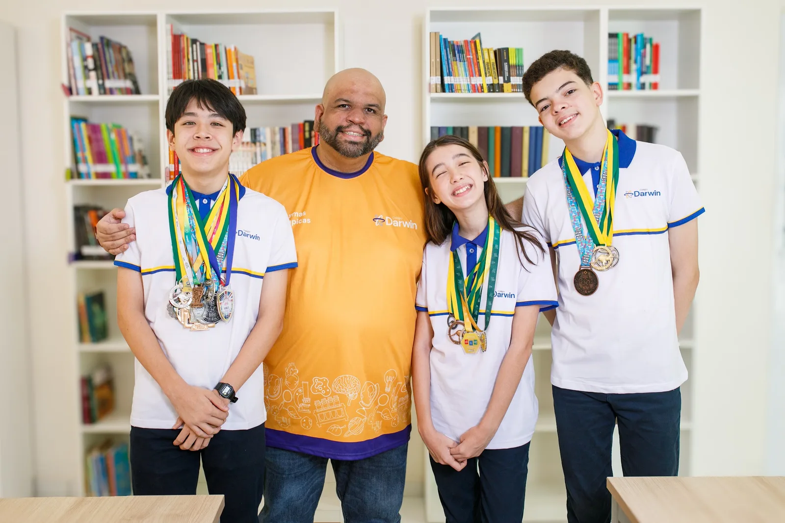 Alunos do Darwin ao lado do professor, com as medalhas conquistadas em olimpíadas do conhecimento.