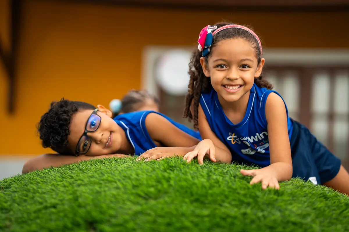 Crianças sorrindo deitadas em área externa do STI.