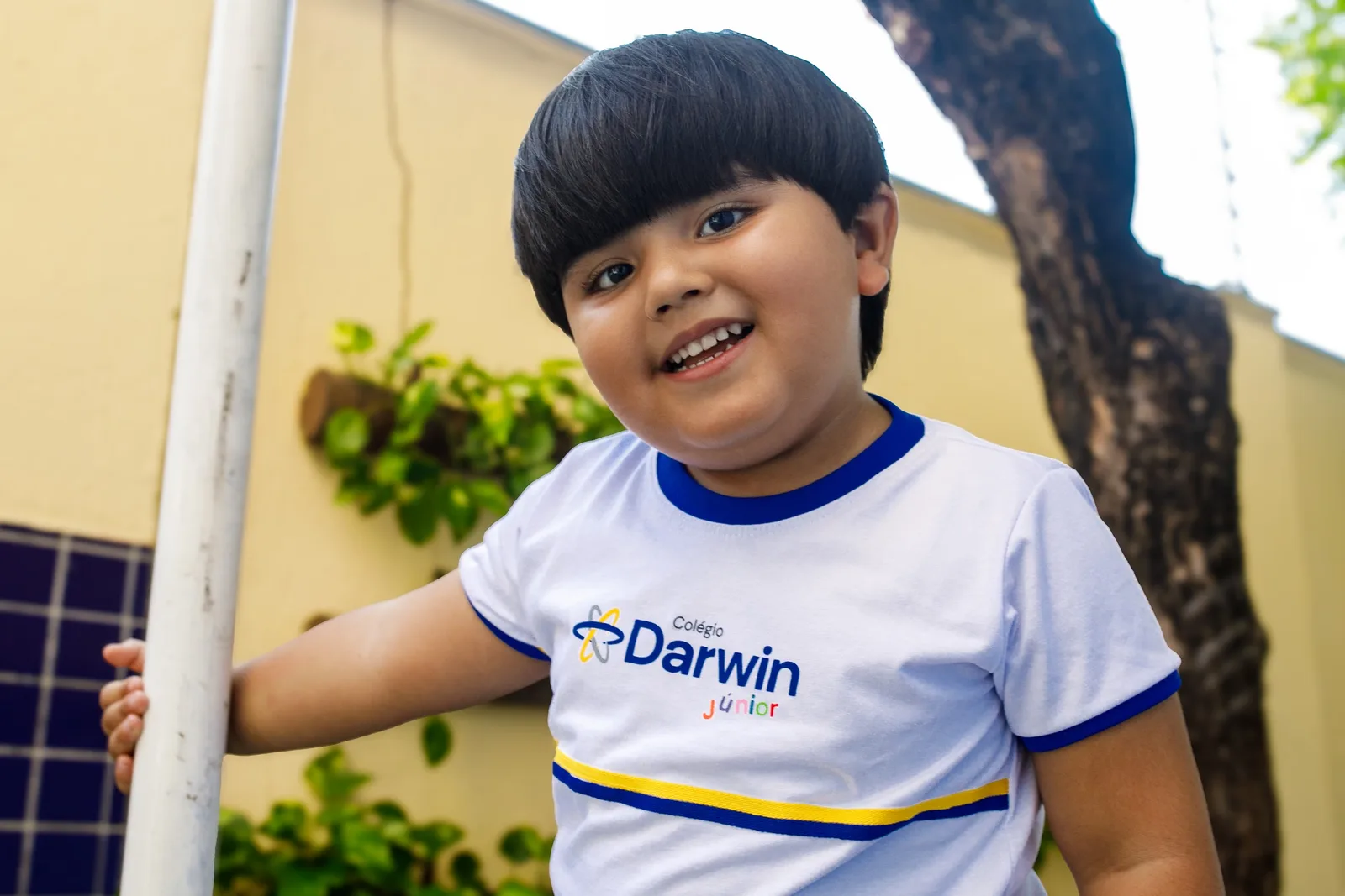 Aluno da Educação Infantil da Sede Aldeota do Colégio Darwin no pátio externo, com o muro amarelo ao fundo