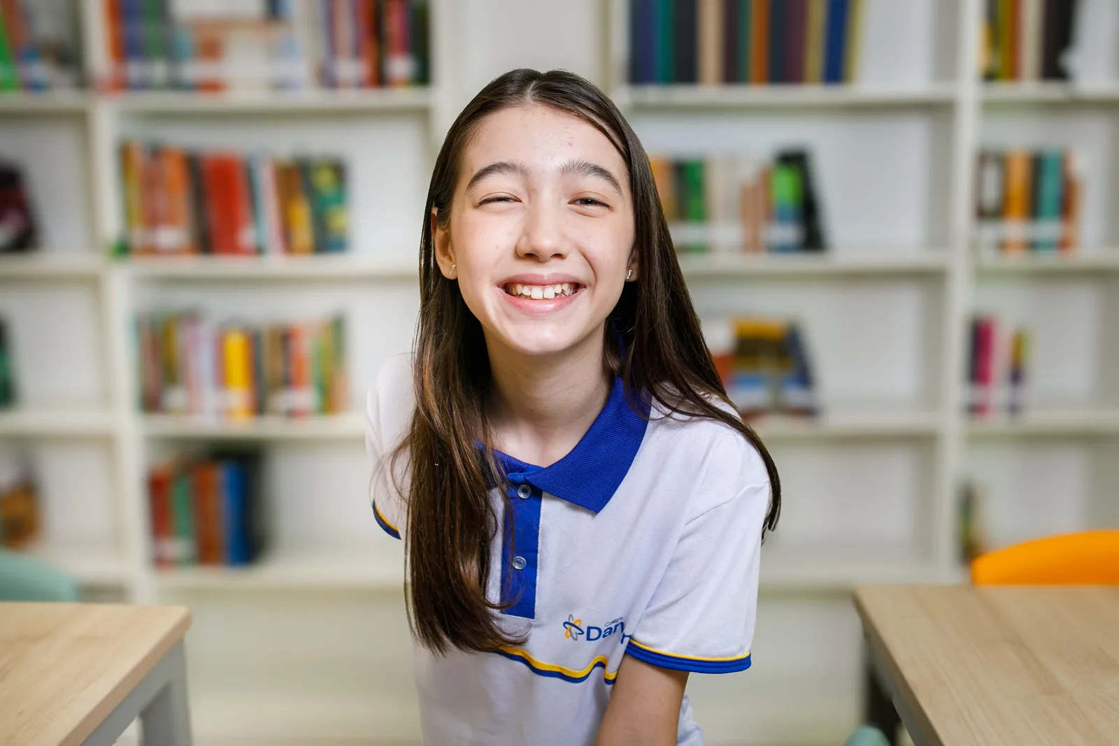 Aluna sorrindo entre as estantes da biblioteca da Sede Dionísio Torres